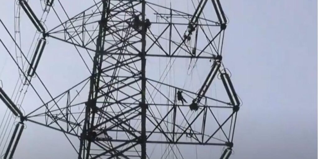 送電鉄塔で高所作業を行うラインマンの遠景