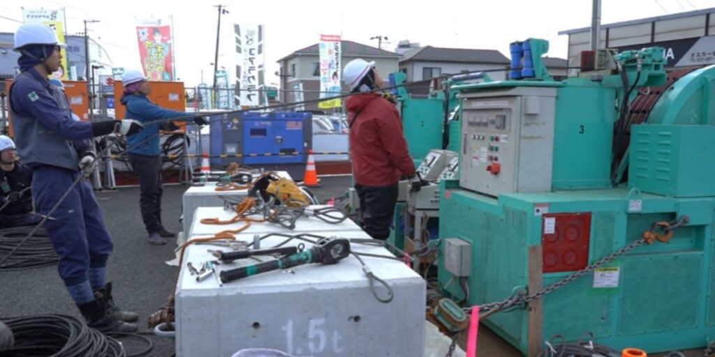 送電線の張り替え作業で、巻き取り機を使ってロープを引くラインマンたち